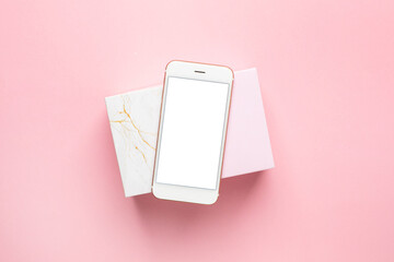 Pink and marble gift present box and mobile phone on pastel pink background