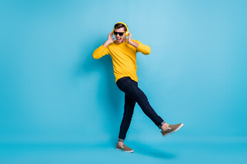 Full body portrait of handsome guy hold arms on headphones open mouth isolated on blue color background