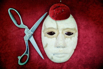 The tailor's scissors lie on a red background with a thimble and spools of thread