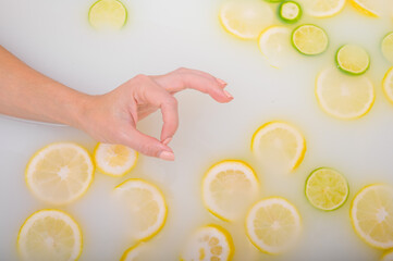 Woman gesturing okay sign and taking a milky citrus bath.