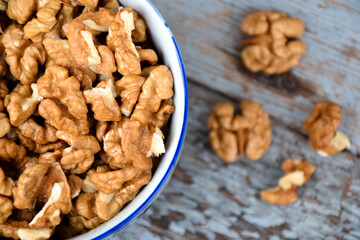 Walnuts. Walnut kernels. Clean organic walnuts. Nuts in the cup on vintage blue wooden background. Walnut tree fresh fall harvest.