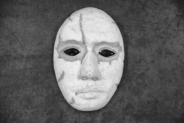 A scary theatrical papier mache mask lies next to a human hand