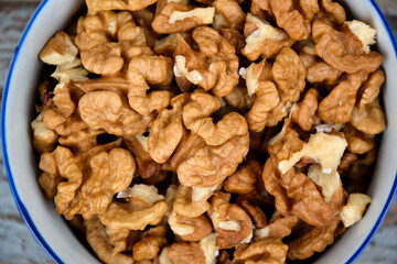 Walnuts. Walnut kernels. Clean organic walnuts. Nuts in the cup on vintage blue wooden background. Walnut tree fresh fall harvest.