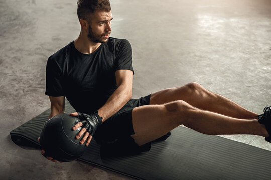 Strong male athlete exercising with ball
