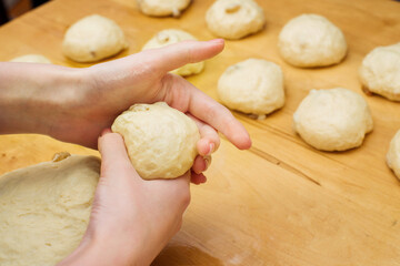 Making dough buns. Female hands knead dough on the kitchen table. homemade baking