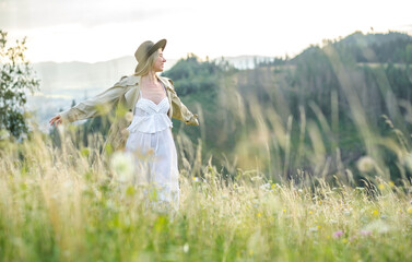Happy woman enjoying sunset stay on the green grass on the forest peak of mountain. Fresh air, Travel, Summer, Fall, Holidays, Journey, Trip, Lifestyle.