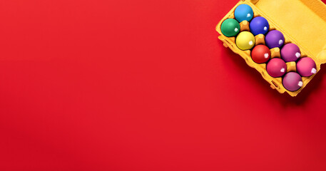 Package of ten chicken eggs with fluffy white tails like Easter bunnies painted in various colors on a solid red background with copy space, empty text place. Banner for the religion holiday. Mockup