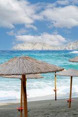 Lots of straw umbrellas on a tropical beach in the sunny day. Ocean shore and sandy coastline with several umbrellas