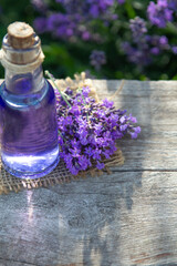 Obraz na płótnie Canvas Lavender Essential oil bottle on wood table and flowers field background