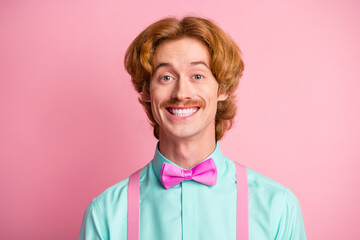 Portrait of young funny smiling cheerful positive good mood guy wear bow tie and suspenders isolated on pink color background