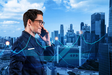 Handsome eastern analyst pensively processing conference call by phone to find financial solution for venture capital project. Hologram chart over Singapore city background