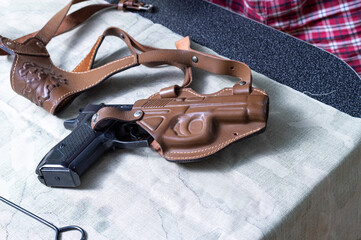 A pistol in a leather holster. The gun is on the table.