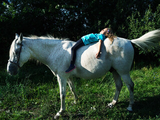 Girl lying on a horse relaxing in sun, Poland