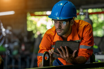 Engineer or factory worker using digital tablet checking inspecting metal component at machine in...