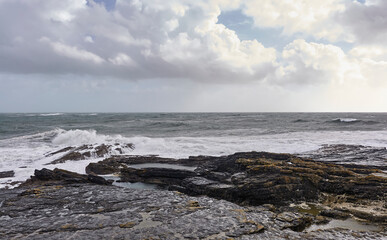 A big storm coming from the west makes landfall at Slade in County Wexford, with large waves and a swell breaking over the rocky Coastline. Eire.