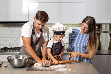 Happy family in the kitchen. Make pizza dough.