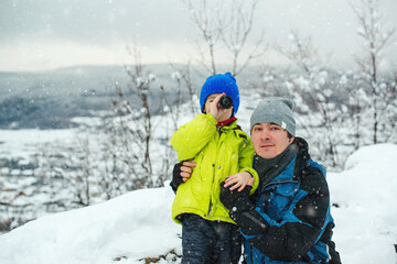 Father and kid having fun together on nature. Father and son hiking in winter mountains.