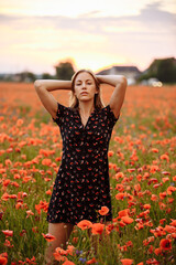 girl in a black dress in a field of poppies