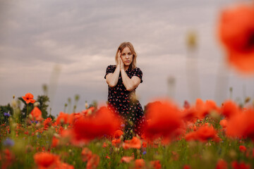 girl in a black dress in a field of poppies