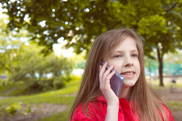 Young beautiful girl teenager talking on smartphone outdoors. Mobile advertising. Side view. Selective focus