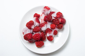Frozen strawberries on a white plate. Strawberries in ice on a white background. Frozen berries.