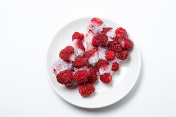 Frozen strawberries on a white plate. Strawberries in ice on a white background. Frozen berries.