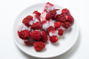 Frozen strawberries on a white plate. Strawberries in ice on a white background. Frozen berries.