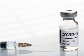 Glass vial with coronavirus vaccine label along with syringe closeup. Space for text