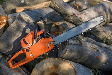 Chainsaw that stands on a heap of firewood in the yard on a background of firewood and trees cut by a chainsaw