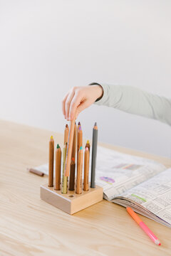 4 year old kid is drawing in her coloring book with thick waldorf style wooden pencils.