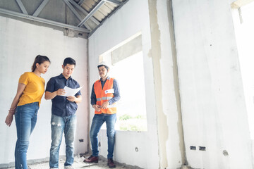 Obraz premium Young asian couple checking house with foreman engineering home inspection building house Walk home inspection with looking and pointing construction for check building home on job site construction