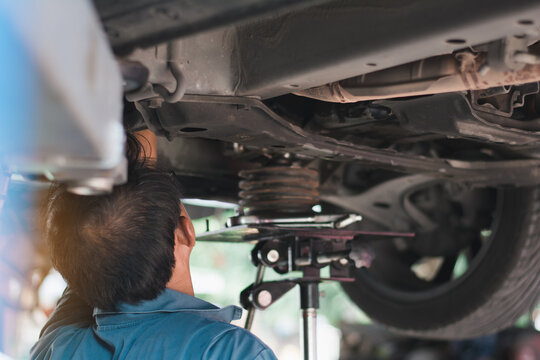 Mid adult mechanic repairing undercarriage of a car in auto repair shop.