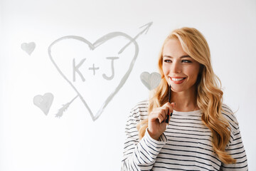 Smiling beautiful young woman drawing a heart symbol