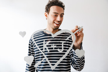 Smiling handsome young man in love drawing a heart symbol
