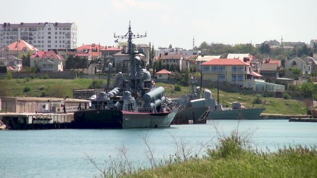 Missile cruiser stands on pier in Quarantine Bay. Close-up. View of cruiser from ruins of ancient city of Chersonesos. Khersones - archaeological reserve. Sevastopol, Crimea, Russia, May 2015 