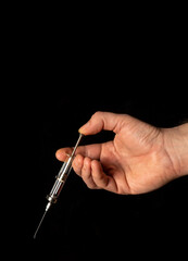 Medical syringe in man hand on black isolated background