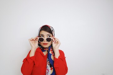 Beautiful woman in retro fashion . Woman in red shirt Sunglasses and blue silk scarf standing over white background.