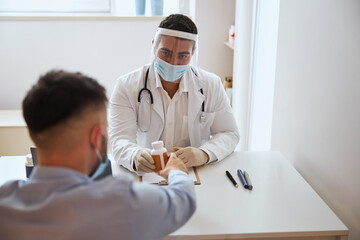 Obraz premium Positive confident male doctor in white uniform discussing with man in front of his