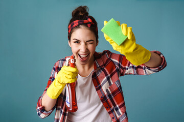 Joyful caucasian woman in gloves winking while cleaning glass