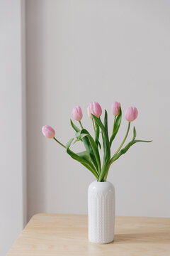 Pink tulips in a white vintage vase in a European Scandinavian styled interior.
