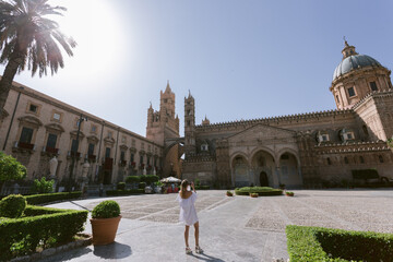 Female taking poto in front of ancient cathedral in  Palermo at sunny summer day.