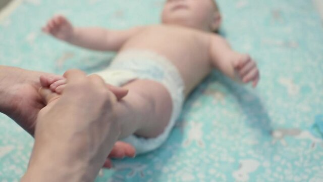 Mother makes foot massage for her baby. Massaging little baby's foot. Close up of little feet of newborn baby