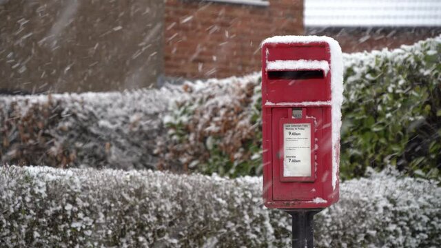 Village red postbox in falling snow	
