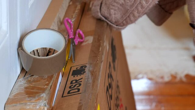 Attaching brown tape to a cardboard box