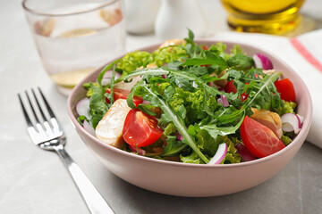 Delicious salad with chicken, arugula and tomatoes on light table, closeup