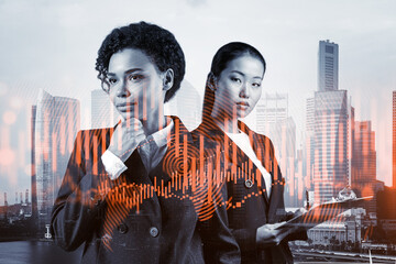 Two young attractive businesswoman in suits pondering about new venture capital and hi-tech start...