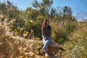 Gentle young lady relaxing on a rock outside