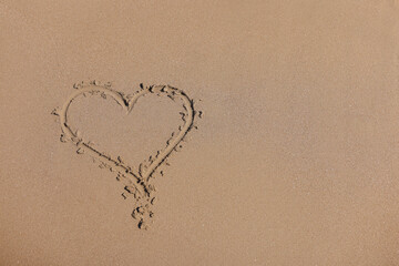 Drawn heart on wet sand next to sea. Love for the sea and travel concept
