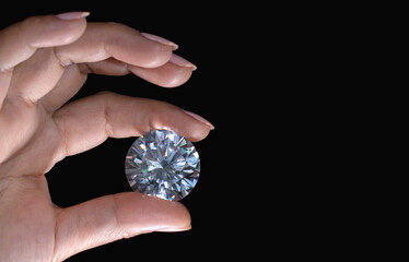 Large round cut diamond in hand on black background with copy space. Luxury concept. High quality...