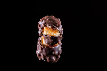 Chocolate candy with caramel and nuts. Broken candy into pieces. Stretching caramel. Chocolate candy isolate.